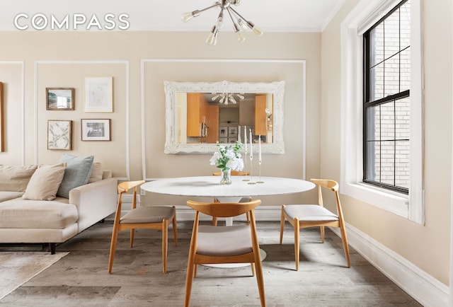 dining room with wood finished floors, a healthy amount of sunlight, baseboards, and a chandelier