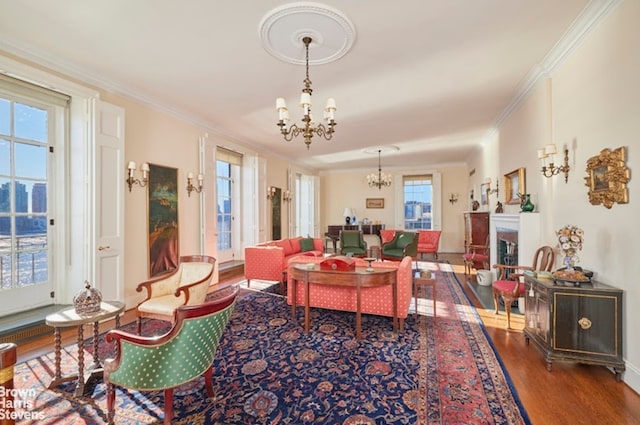 living area with ornamental molding, a fireplace, an inviting chandelier, and wood finished floors