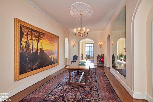 office space featuring wood finished floors, baseboards, an inviting chandelier, arched walkways, and ornamental molding