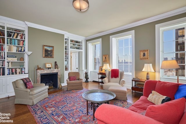 living area featuring wood finished floors, crown molding, a healthy amount of sunlight, and a premium fireplace