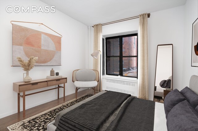 bedroom featuring radiator heating unit, wood finished floors, and baseboards