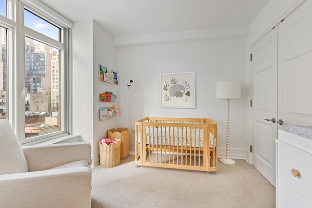 bedroom featuring light colored carpet, a nursery area, and baseboards