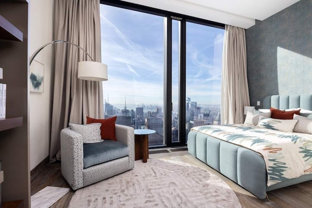 bedroom featuring a city view, wood finished floors, and an accent wall