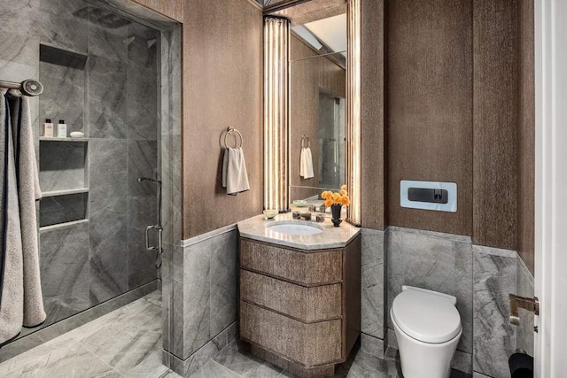 bathroom featuring a wainscoted wall, toilet, tile walls, a shower stall, and vanity