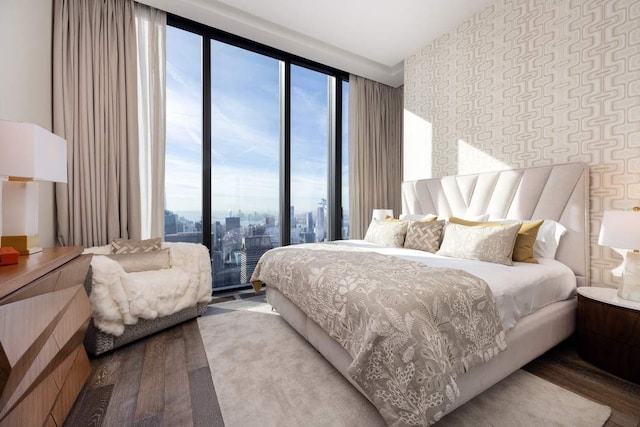 bedroom with expansive windows, wallpapered walls, and wood finished floors