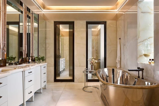 full bathroom with marble finish floor, vanity, and a freestanding tub