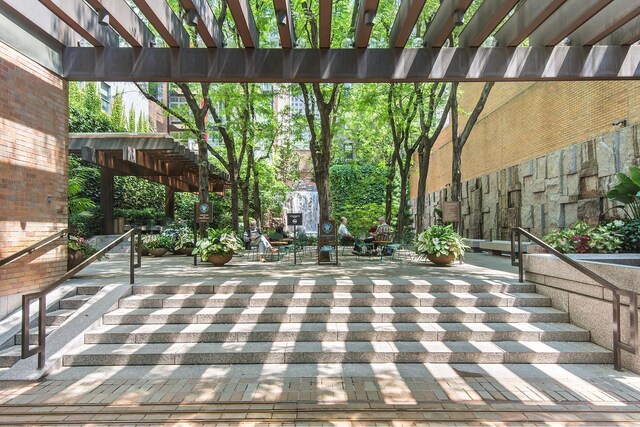 doorway to property featuring brick siding and a pergola