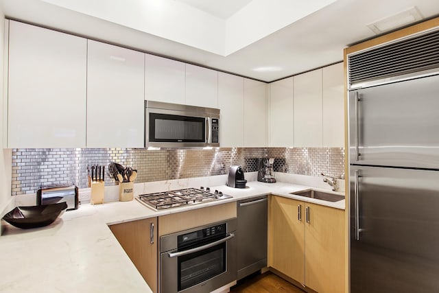 kitchen featuring a sink, modern cabinets, backsplash, and appliances with stainless steel finishes