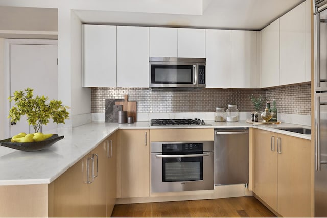 211 E 51st St Unit 10C, New York City, NY 10022 - kitchen with appliances with stainless steel finishes, backsplash, white cabinets, dark wood-style flooring, and modern cabinets
