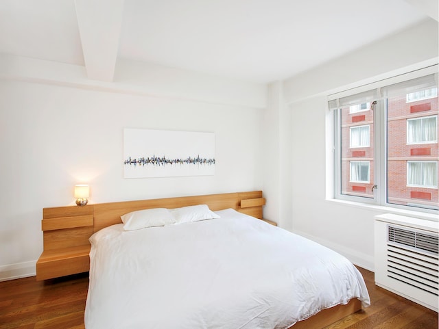 bedroom featuring beamed ceiling, baseboards, and wood finished floors