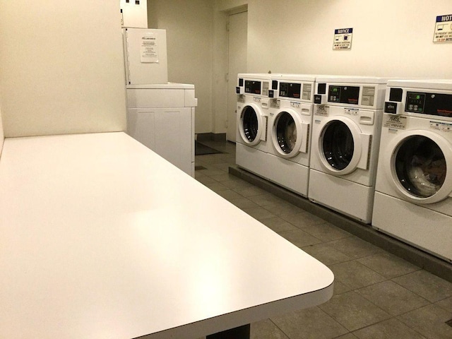 communal laundry room featuring washer and clothes dryer and dark tile patterned floors