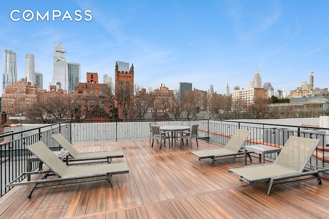 wooden terrace with outdoor dining area and a view of skyline