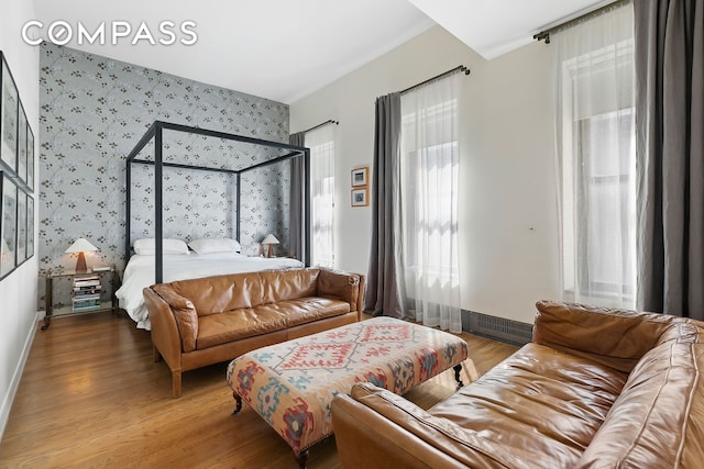bedroom with wallpapered walls, wood finished floors, and baseboards