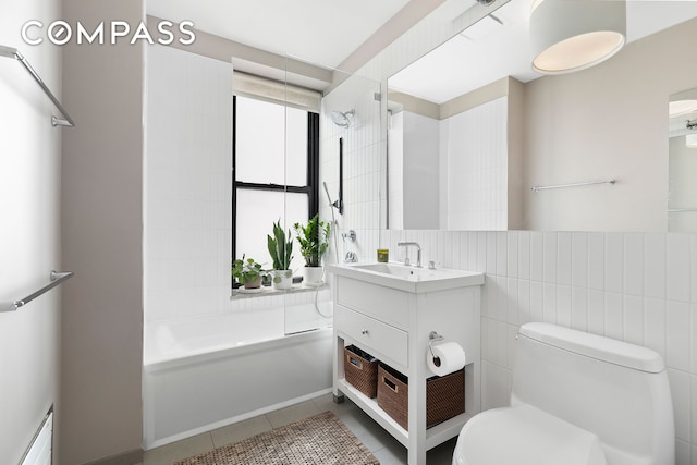 bathroom with vanity, tile patterned flooring, shower / washtub combination, tile walls, and toilet