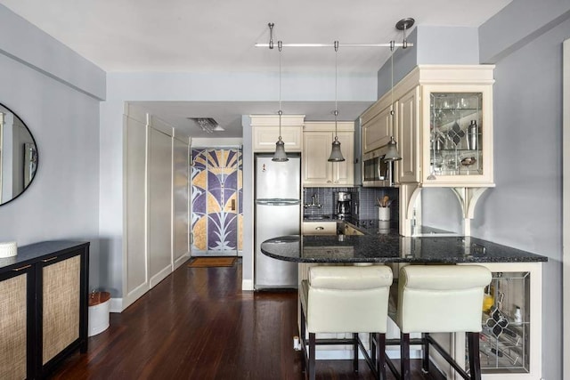 kitchen with backsplash, a breakfast bar, dark stone countertops, dark wood-style floors, and stainless steel appliances