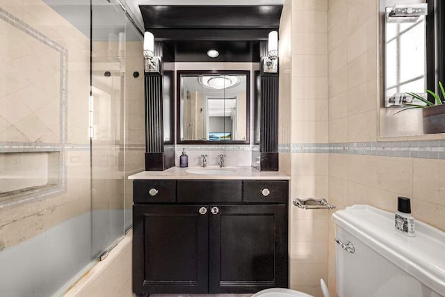 full bathroom with vanity, toilet, tile walls, and shower / bath combination with glass door