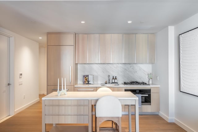 kitchen with modern cabinets, a sink, light brown cabinets, and oven