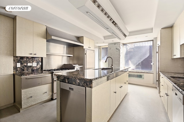 kitchen with backsplash, an island with sink, dark stone countertops, stainless steel appliances, and a sink