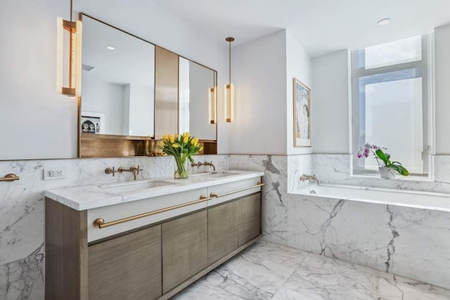 bathroom with double vanity, a garden tub, marble finish floor, and a sink