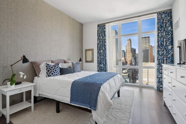 bedroom featuring visible vents, wallpapered walls, and wood finished floors