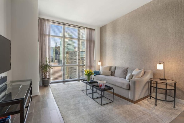 living room featuring expansive windows, wallpapered walls, baseboards, and wood finished floors