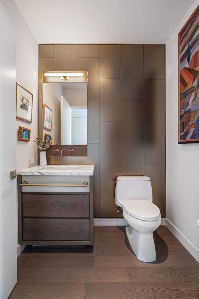 bathroom featuring vanity, toilet, wood finished floors, and baseboards