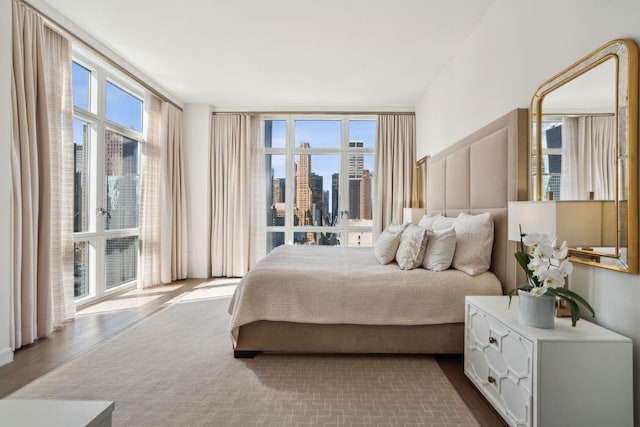 bedroom with access to exterior, a city view, expansive windows, and dark wood-style flooring