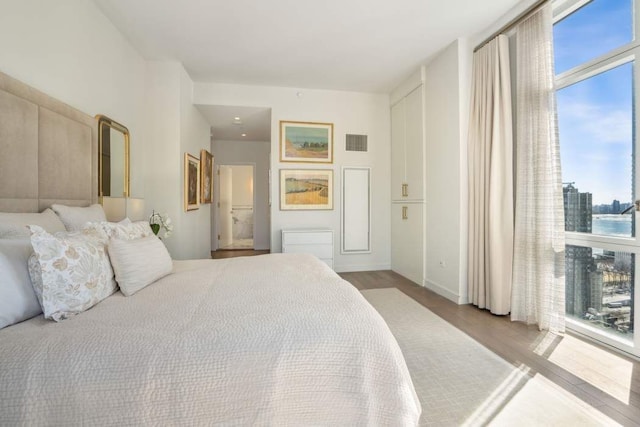 bedroom with visible vents, multiple windows, and wood finished floors