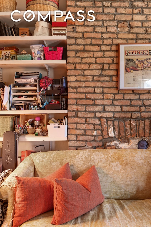 living area with brick wall and wood finished floors