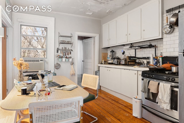 kitchen featuring white cabinetry, decorative backsplash, light wood-type flooring, and stainless steel gas range