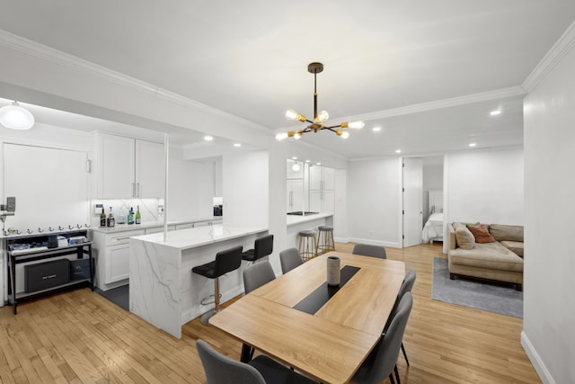 dining room with a notable chandelier, recessed lighting, light wood finished floors, and ornamental molding