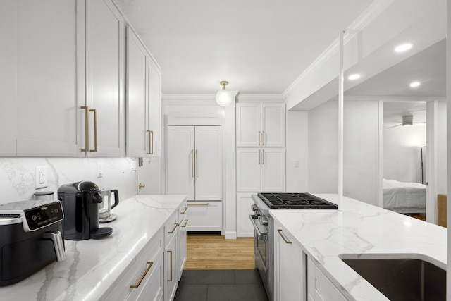 kitchen featuring high quality appliances, ornamental molding, a sink, tasteful backsplash, and white cabinetry