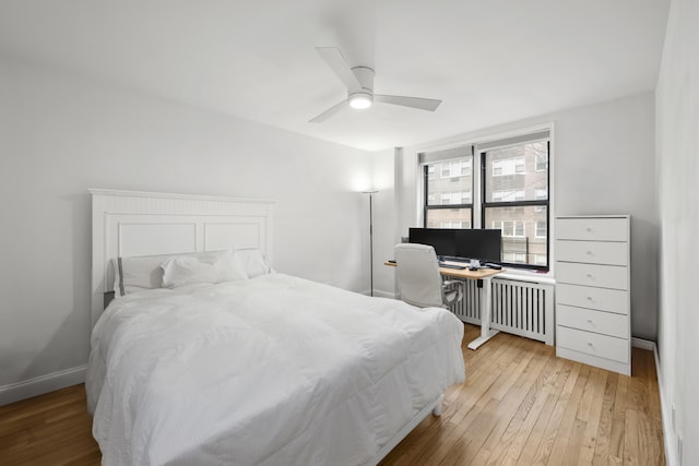 bedroom featuring ceiling fan, baseboards, radiator, and light wood-style flooring