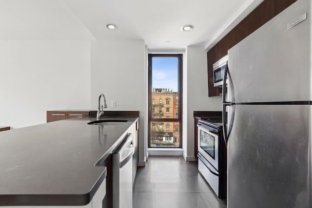 kitchen with a sink, stainless steel appliances, dark countertops, and recessed lighting