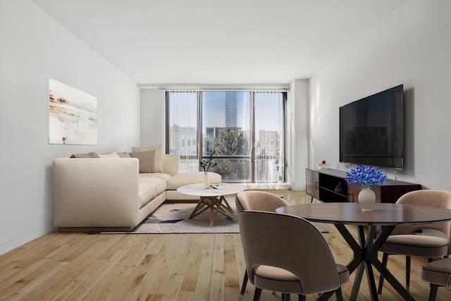 living area with light wood-style flooring, a wall of windows, and baseboards