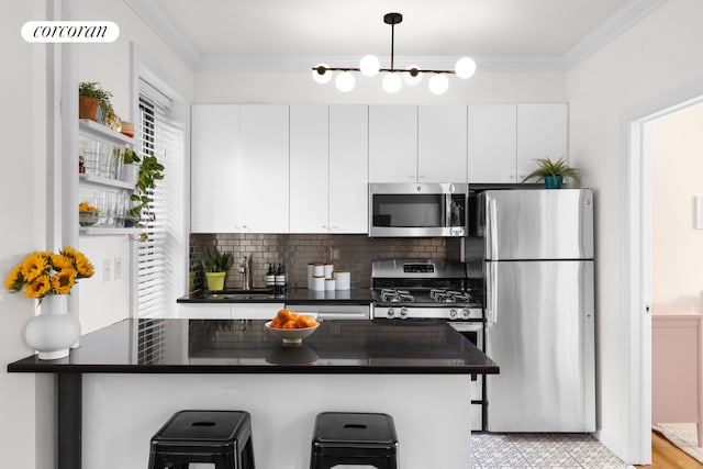 kitchen with a breakfast bar area, dark countertops, appliances with stainless steel finishes, and ornamental molding