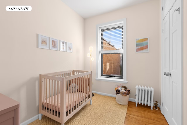 382 Prospect Pl Unit 15, New York City, NY 11238 - bedroom featuring radiator heating unit, a nursery area, baseboards, wood finished floors, and a closet