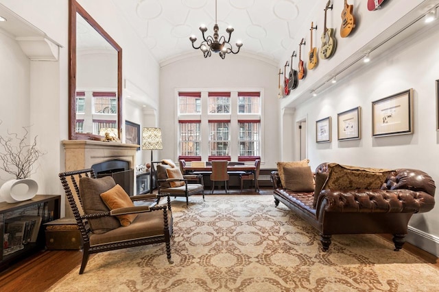 sitting room with a chandelier, a fireplace, lofted ceiling, and wood finished floors