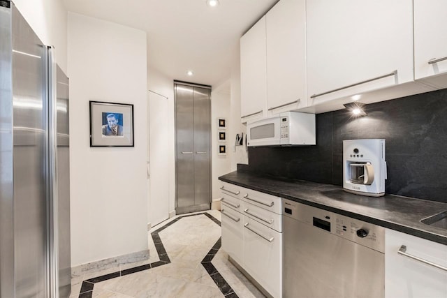 kitchen featuring dark countertops, backsplash, white cabinetry, recessed lighting, and stainless steel appliances