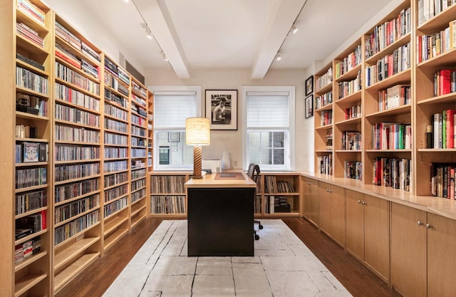 interior space featuring beam ceiling, wood finished floors, rail lighting, and bookshelves