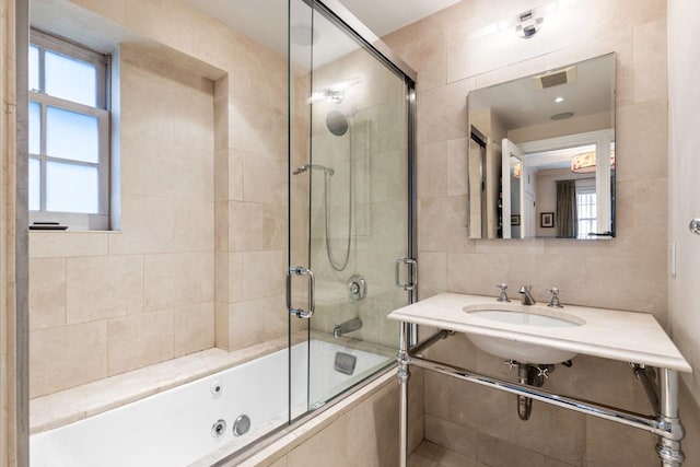 bathroom featuring tiled shower / bath, visible vents, a sink, backsplash, and tile walls