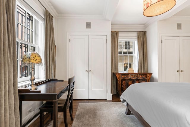 bedroom featuring visible vents, crown molding, and wood finished floors