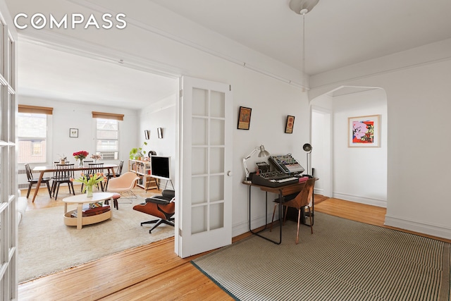 interior space featuring arched walkways, french doors, baseboards, and wood finished floors