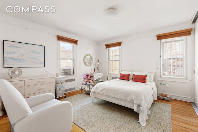 bedroom featuring radiator, baseboards, and light wood-style floors