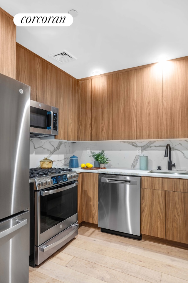 kitchen with visible vents, a sink, stainless steel appliances, modern cabinets, and backsplash