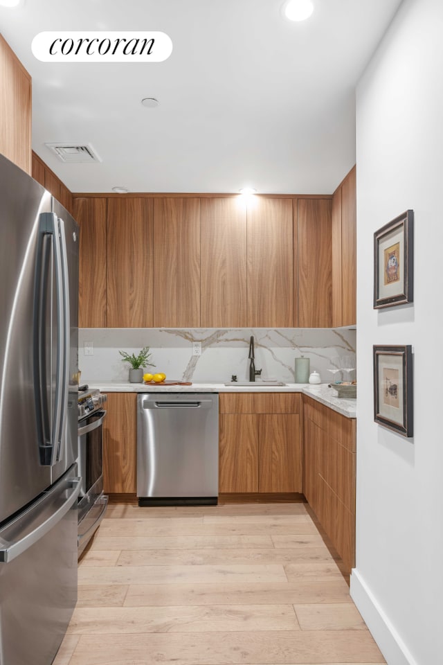 kitchen with a sink, modern cabinets, appliances with stainless steel finishes, and light countertops