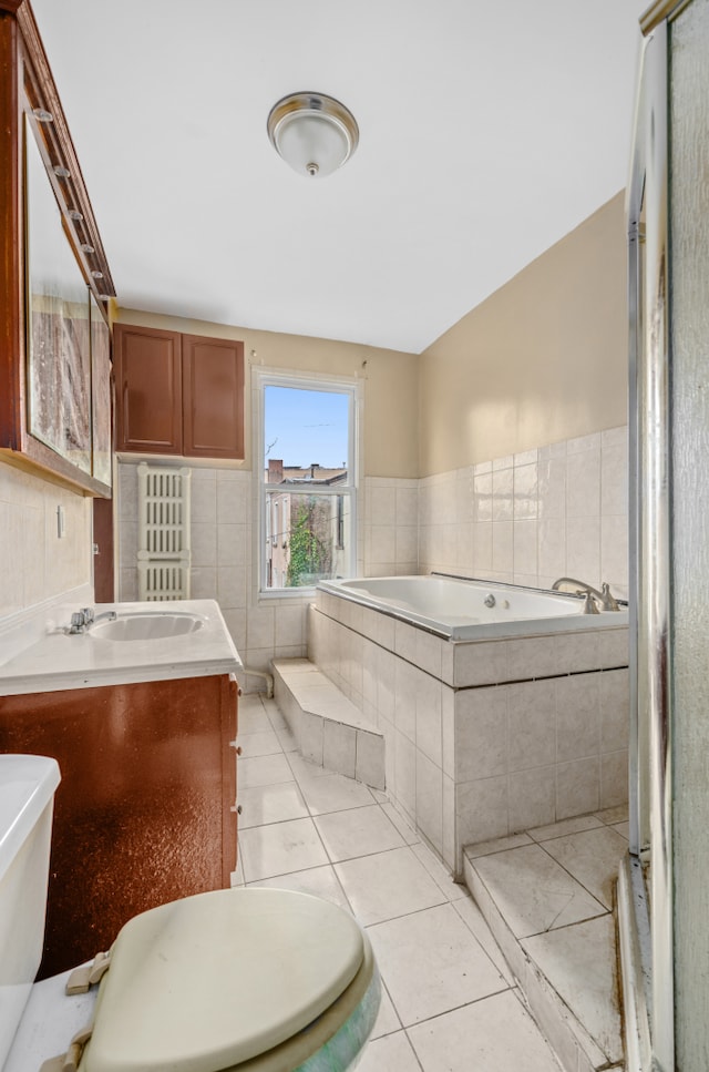 full bathroom with tile patterned flooring, a relaxing tiled tub, and vanity