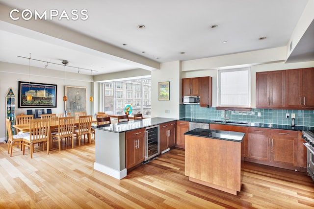 kitchen featuring a peninsula, a sink, wine cooler, light wood-style floors, and stainless steel microwave