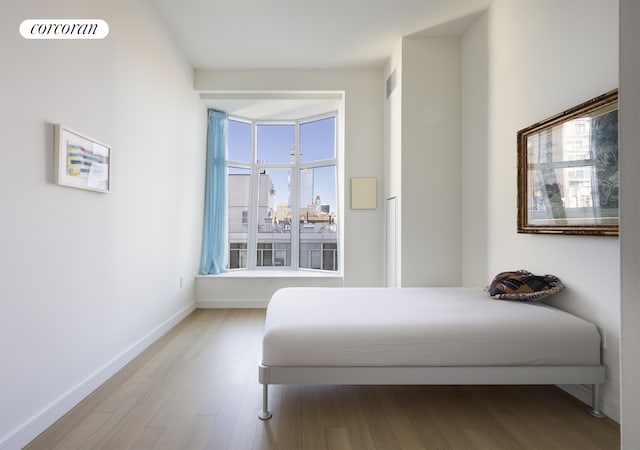 bedroom with wood finished floors, visible vents, and baseboards