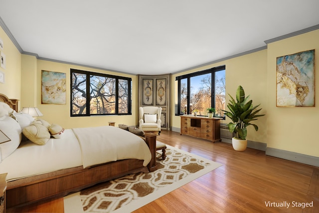 bedroom featuring baseboards, wood finished floors, and crown molding